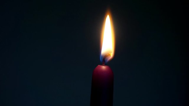 Burning violet candle against a dark background, calming and relaxing