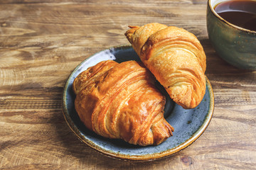 Coffee and croissant on rustic wooden table. French breakfast. Top view. Flat lay. Copy space.