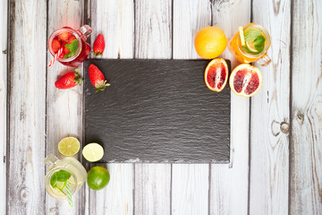 Summer drinks. Fresh freshes on a slate board. View from above. Orange, lemon and strawberry fresh.