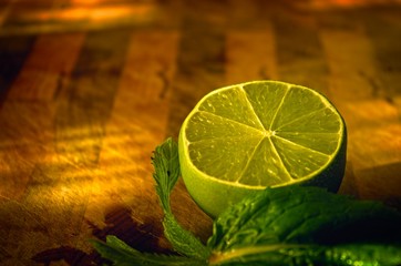 Green lime half on timber chopping board with mint leaves