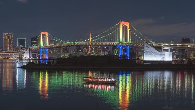 Odaiba, Tokyo. Rainbow Bridge at night with special light up with reflection and boat
