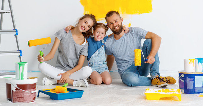Repair in apartment. Happy family mother, father and child daughter  paints wall
