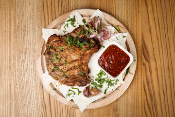 Delicious grilled pork chop served on wooden table, top view
