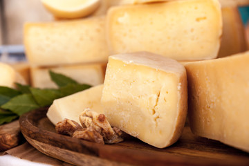 Hard cow cheese on the wooden board decorated with dried figs