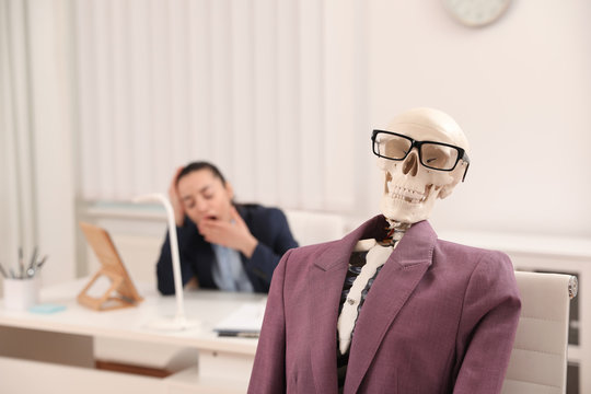 Human skeleton with suit and glasses in office. Space for text