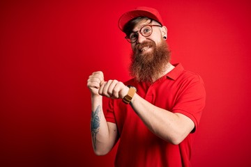 Young handsome delivery man wearing glasses and red cap over isolated background Pointing to the back behind with hand and thumbs up, smiling confident