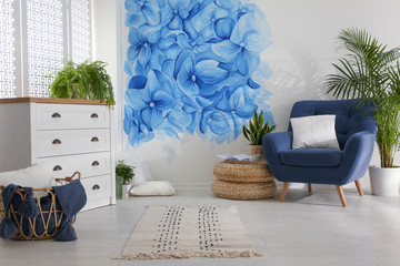 Stylish living room with blue flowers painted on wall. Floral pattern in interior design