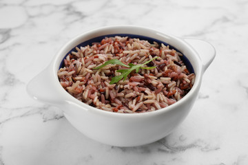 Tasty brown rice on marble table, closeup