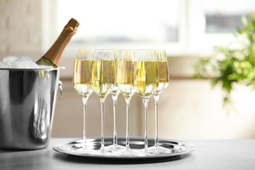 Glasses of champagne and ice bucket with bottle on grey table