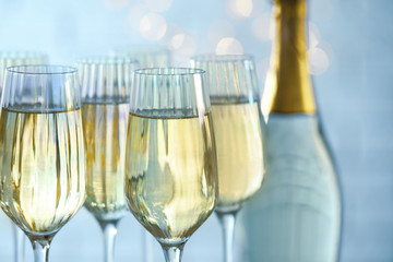 Glasses and bottle of champagne against blurred lights, closeup