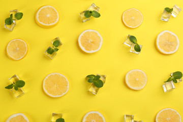 Lemonade layout with juicy lemon slices, ice and mint on yellow background, top view