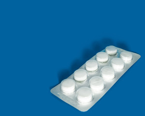 Pharmaceutical preparation.  Blister with tablets on a blue background. Medicine