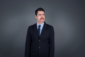 Photo of amazed puzzled young Caucasian male, curves lips and has worried look, sees something awful in front, isolated on white background, dressed in jean overalls.