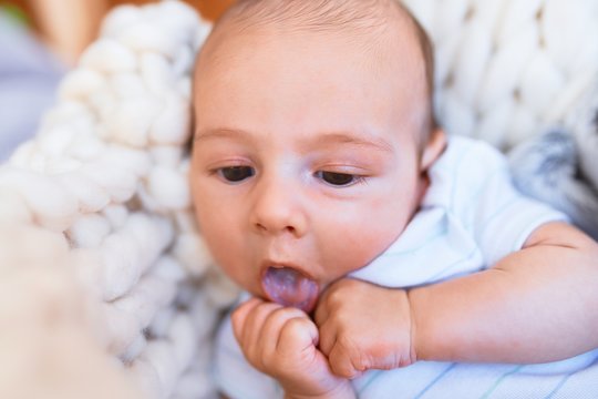 Adorable baby lying down over blanket on the floor at home. Newborn relaxing and resting comfortable