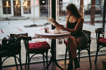Young woman reading book in cafe
