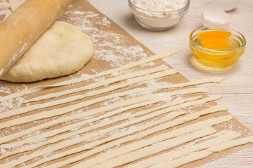 Dough cut into strips. Eggs and flour on table