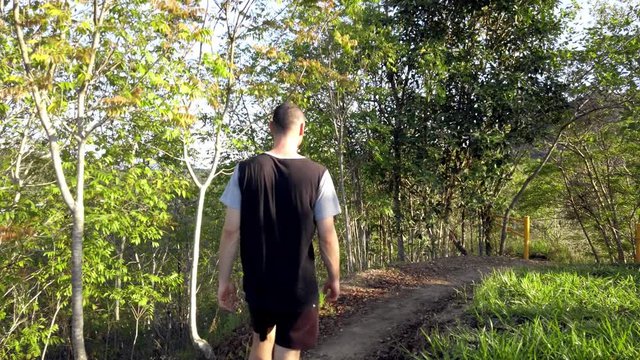 A man walking on trails of luch green Rain Forest in Cairns Queensland, Australia, - wide rolling slow motion