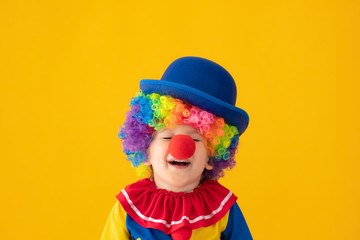 Funny kid clown playing against yellow background