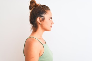 Young redhead woman wearing a bun over isolated background looking to side, relax profile pose with natural face with confident smile.