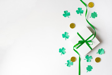 Composition for St. Patrick's Day. Gift white box with a green satin bow, clover and toy gold coins...