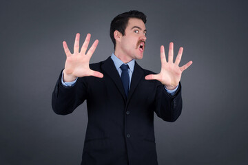 Dissatisfied male model frowns face, has disgusting expression, shows tongue, expresses non compliance, irritated with somebody, rejects do something. People and negative facial expressions