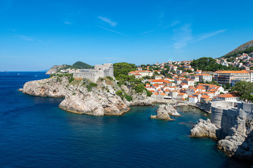 Fototapeta na wymiar Fort Lovrijenac and Pile Harbour in Dubrovnik, Croatia. A view from above looking towards a rocky harbour and a fort positioned on a rocky outcrop surrounded by the Adriatic sea.