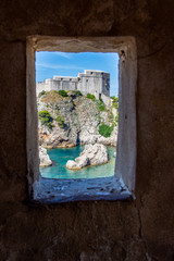 Fort Lovrijenac in Dubrovnik, Croatia part of the UNESCO World Heritage Site is framed by the old city walls. A fortress is perched on the Adriatic coast which is a turquoise blue.