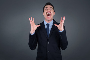 Screaming, hate, rage. Crying emotional angry man screaming on blue studio background. Emotional, young face. Female half-length portrait. Human emotions, facial expression concept. Trendy colors