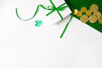 The composition of the St. Patrick's day. White gift box with a green bow, a piece of paper clover...