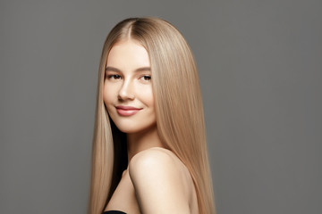 Hairl care shampoo.Beautiful young woman with long healthy hair posing against grey background. Beauty salon concept
