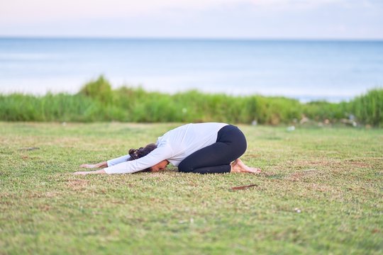 Young beautiful sportwoman practicing yoga. Coach teaching postures at park