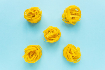 Uncooked wheat pasta nests on a blue background