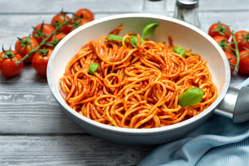 Close up of spaghetti with tomato suace in a pan on black background