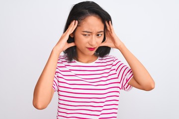Young chinese woman wearing striped t-shirt standing over isolated white background with hand on head for pain in head because stress. Suffering migraine.