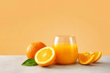 Poster Close up of orange juice in a glass with oranges against trendy yellow background © Katecat