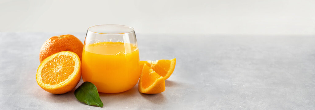 Fresh orange juice glass and oranges on light background