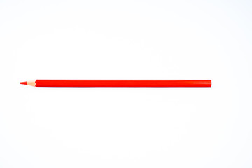 A sharpened red colored pencil crayon is isolated on a white background