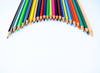 Pencil crayons arranged in a waved formation over an isolated white background
