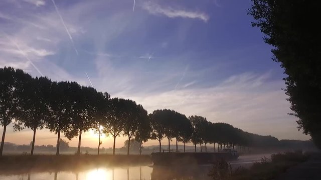 Barge on the schelde river in the amazing morning light with fog