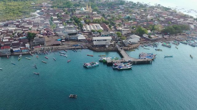 Aerial, descending, drone shot towards the harbor at the Tanjung Luar Fish Market, on a sunny day, in Lombok, West Nusa Tenggara, Indonesia