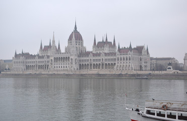 Obraz premium Ship on Danube river, Parliament in the fog background