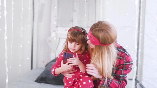 little daughter and mom taking pictures on the phone in red pajamas