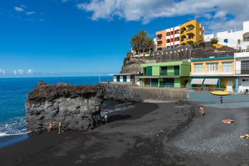 Puerto Naos beach an sunbathing people at beach with black lava sand at La Palma, Canary Island, Spain.