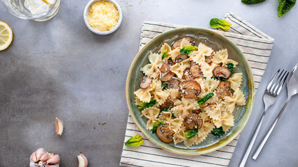 tasty pasta with mushrooms and spinach on a gray concrete background. banner, copy space