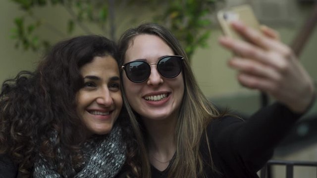 two young attractive women having fun, making silly duck faces and taking selfies on vacation. 4K