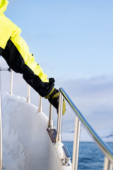 Sailor in the north arctic sea with snow and ice leaning and supporting on a metal handrail wearing...