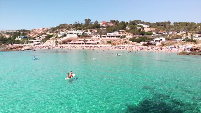 two beautiful girls enjoying a stand up paddle board in turqoise waters in ibiza spain