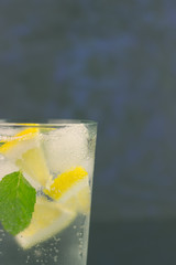Lemonade with fresh lemon and mint leaves on copy space background
