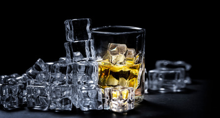 Whiskey on the rocks, whiskey glass, ice cubes on a slate board