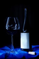 Wine bottle, glass and cork on blue fabric